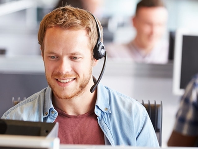 Junger Mann lächeln am Computer mit Headset